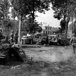 Trois soldats américains contemplent des épaves de véhicules à Mortain
