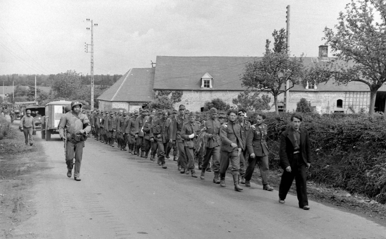 Colonne de prisonniers allemands croise un convoi de véhicules américains dont une ambulance, Hameau de La Chaussée, Sainte marie du Mont 8 juin 1944