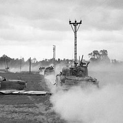 Sherman tanks move up past a crash-landed Spitfire, for an attack on (…)