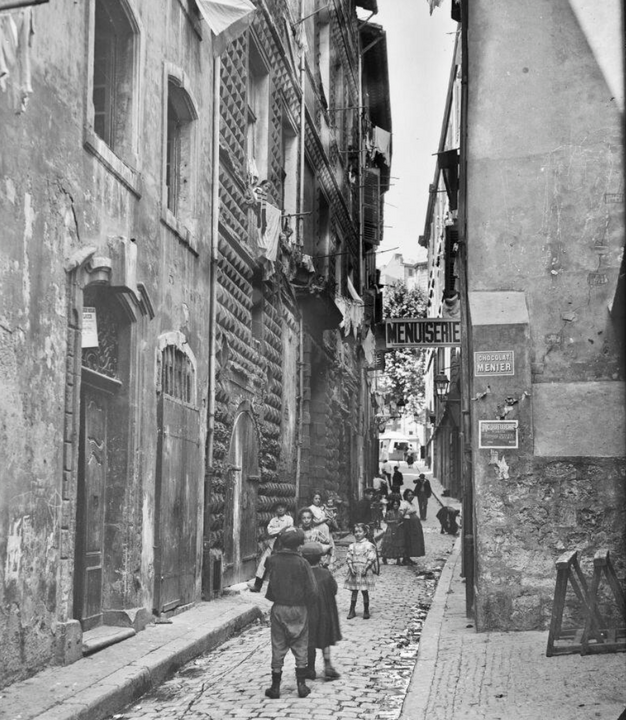 la rue de la Prison vue dans l'axe et la façade de la maison Diamantée ; de nombreux enfants jouent dans la rue - [1909-1910]