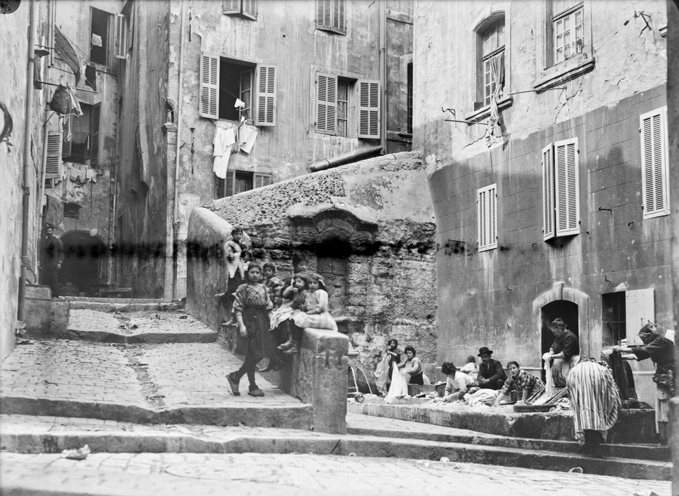 115 Fi 1159 - Marseille (Bouches-du-Rhône) : des femmes lavent le linge au lavoir de la rue Fontaine-Saint-Laurent ; un groupe d'enfants ; les façades des maisons environnantes - [c. 1913]