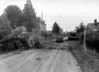 Un char Sherman et un canon automoteur allemand Sturmgeshütz (StuG III) détruits, de part et d'autre de la D5 à l'entrée Ouest de Juvigny Le Tertre, début aout 1944 
