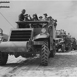 A column of halftrac armored cars waits for orders to proceed to a practice (…)